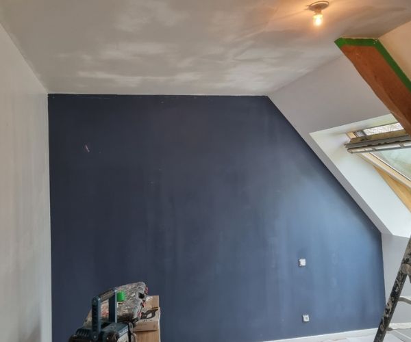 Application d’une peinture bleue sur un mur de chambre à Brest par Ouest Déco.