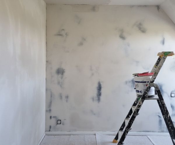 Préparation des murs avant peinture et pose de papier peint dans une chambre à Brest.